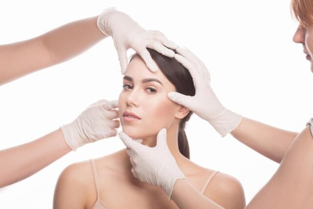 handmade-beauty-beautiful-young-woman-keeping-eyes-opened-while-four-hands-medical-gloves-touching-her-face-isolated-white-background_549566-807